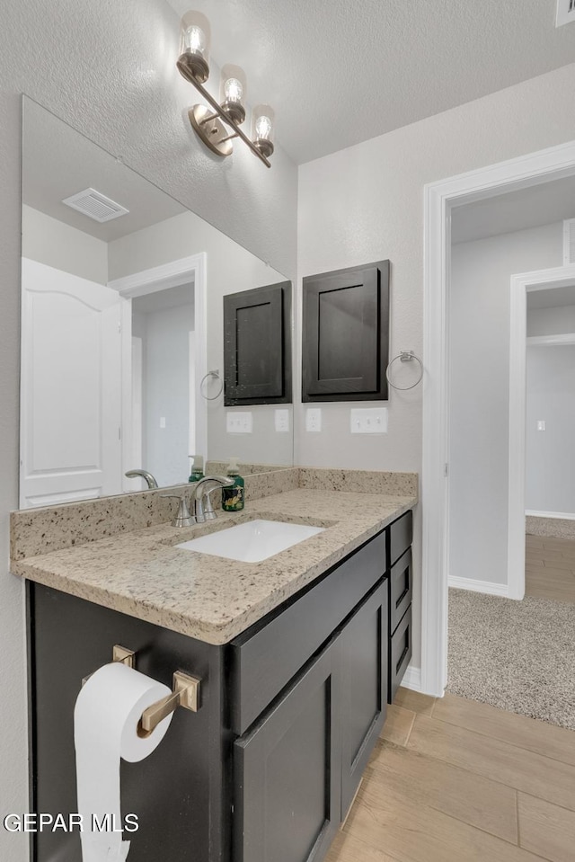13868 Sky Ranger Ave, El Paso, TX 79928 - bathroom featuring a textured ceiling, wood finished floors, vanity, and baseboards