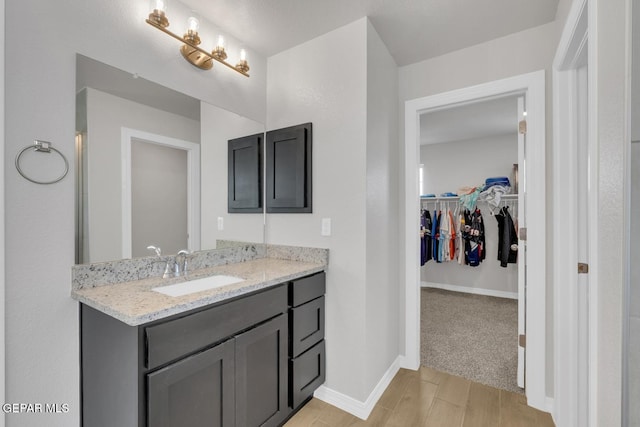 13868 Sky Ranger Ave, El Paso, TX 79928 - bathroom with a spacious closet, vanity, wood finished floors, and baseboards