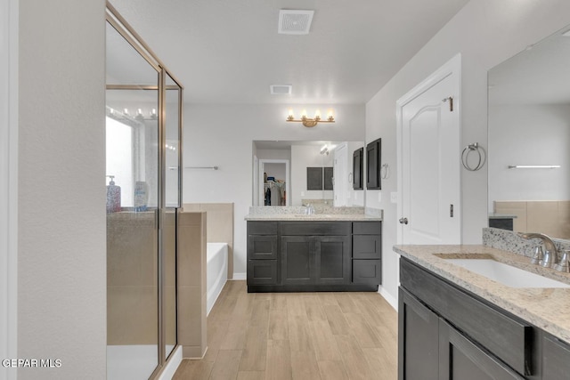 13868 Sky Ranger Ave, El Paso, TX 79928 - full bath featuring a stall shower, two vanities, a bath, and wood finished floors