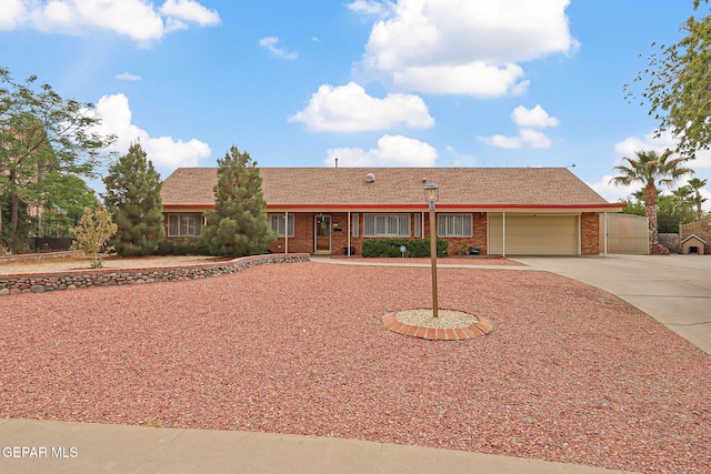 single story home featuring a garage, concrete driveway, brick siding, and fence