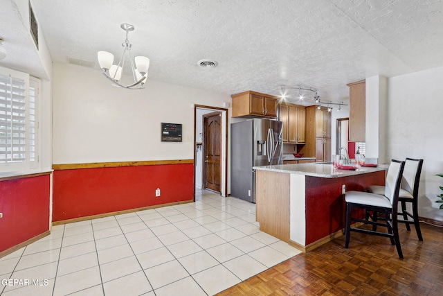 kitchen featuring stainless steel fridge, a chandelier, a textured ceiling, a peninsula, and baseboards