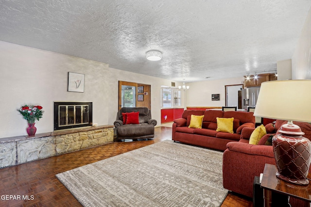 living area featuring a chandelier, a textured ceiling, and a fireplace