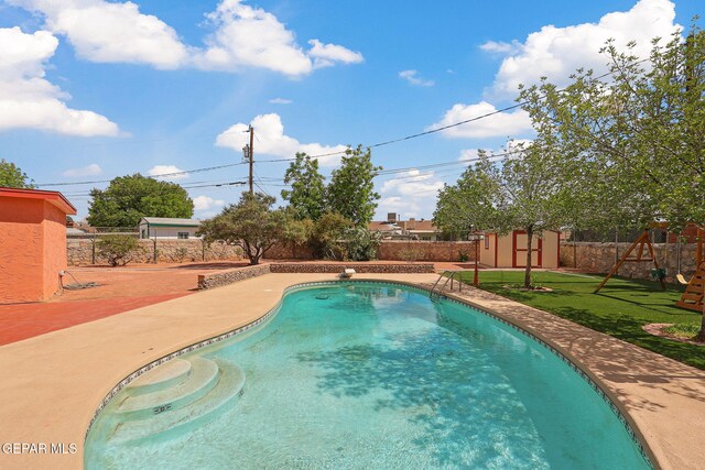 view of swimming pool featuring a storage unit, an outdoor structure, and a playground