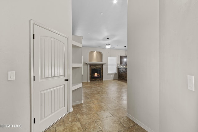 corridor with baseboards and stone tile flooring