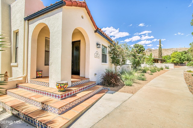 property entrance with stucco siding and a tile roof