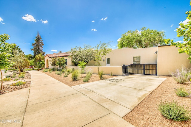 view of side of home with a gate, stucco siding, and fence