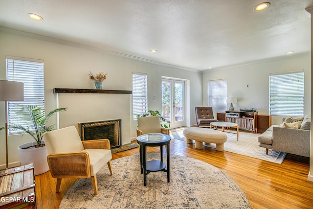 living area featuring crown molding, wood finished floors, recessed lighting, and a fireplace