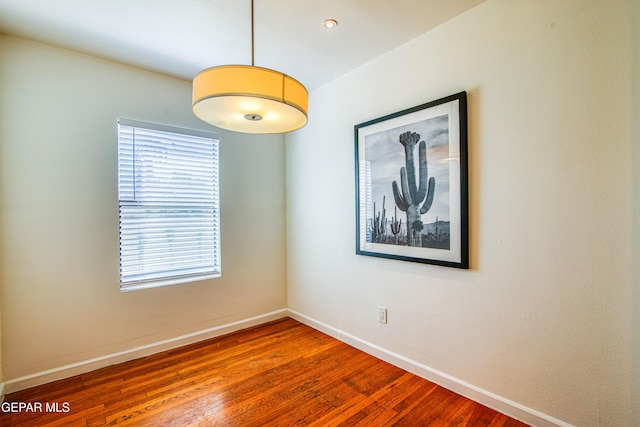 spare room with baseboards and hardwood / wood-style flooring