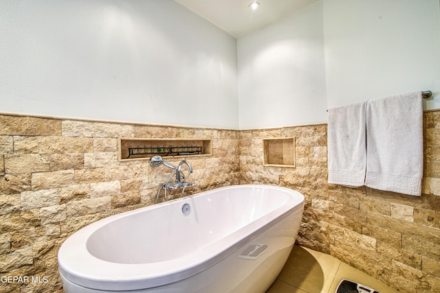 bathroom featuring tile walls, a soaking tub, lofted ceiling, and a wainscoted wall