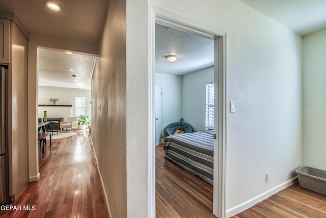 corridor with wood finished floors, baseboards, and recessed lighting