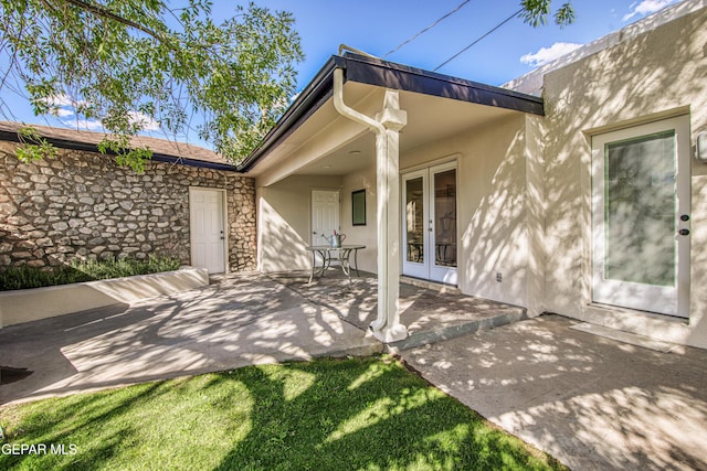 rear view of house with french doors, stucco siding, a patio, and stone siding