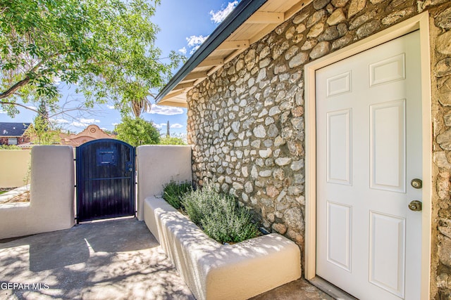 doorway to property with stone siding, a gate, and fence