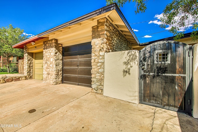 view of property exterior featuring stone siding, concrete driveway, and a garage