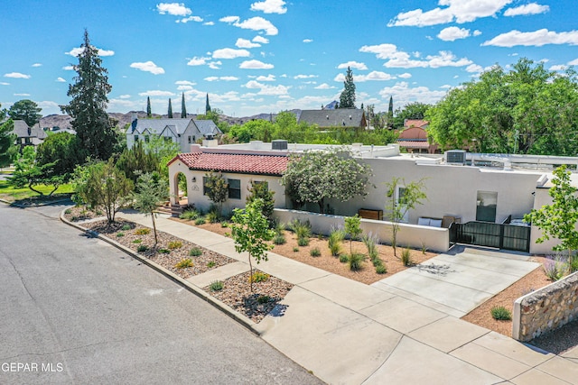 view of front of house with a gate, a fenced front yard, stucco siding, a tile roof, and a residential view