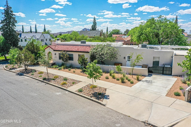 view of front facade featuring a gate, a fenced front yard, stucco siding, a tiled roof, and a residential view