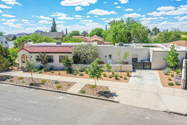 view of front facade featuring stucco siding, a gate, a fenced front yard, a tiled roof, and a chimney