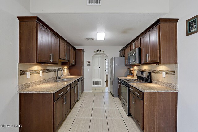 14182 John Scagno, El Paso, TX 79938 - kitchen with a sink, stainless steel appliances, visible vents, arched walkways, and decorative backsplash