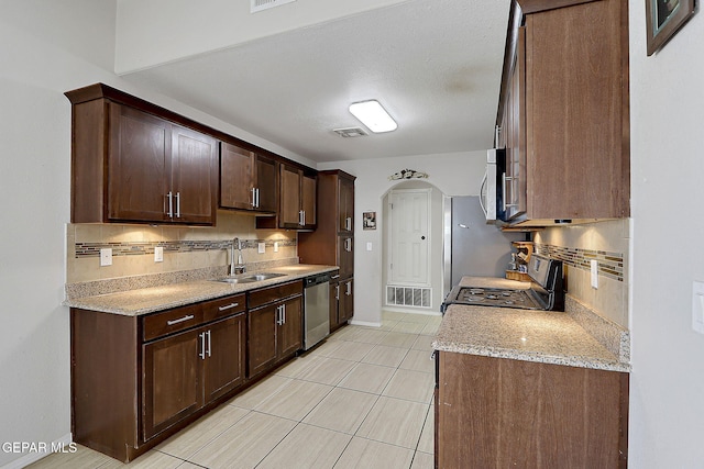 14182 John Scagno, El Paso, TX 79938 - kitchen featuring decorative backsplash, stainless steel appliances, dark brown cabinets, and a sink