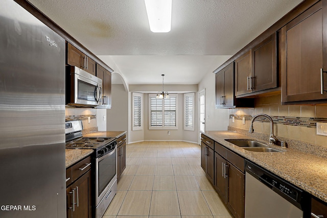 14182 John Scagno, El Paso, TX 79938 - kitchen with a sink, dark brown cabinetry, decorative backsplash, baseboards, and appliances with stainless steel finishes