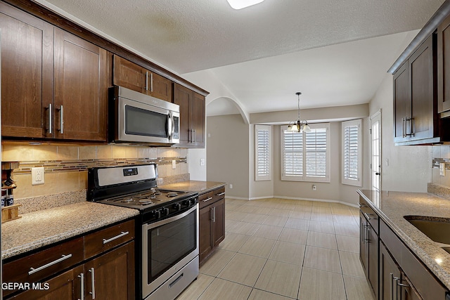 14182 John Scagno, El Paso, TX 79938 - kitchen with backsplash, baseboards, light stone counters, and appliances with stainless steel finishes
