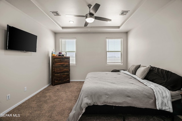 carpeted bedroom featuring baseboards, a raised ceiling, multiple windows, and visible vents