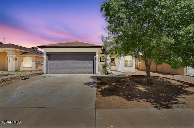 view of front of house featuring concrete driveway, an attached garage, and stucco siding