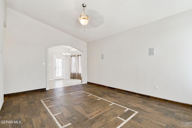 empty room featuring arched walkways, baseboards, parquet floors, and ceiling fan with notable chandelier