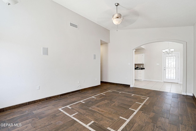 interior space with light wood finished floors, visible vents, ceiling fan with notable chandelier, and arched walkways