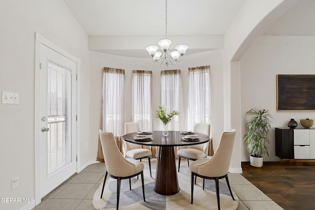 dining area featuring a chandelier, a wealth of natural light, arched walkways, and baseboards