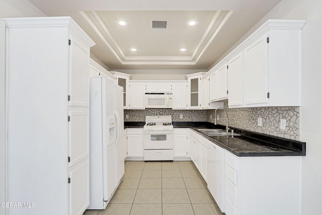 kitchen featuring a sink, white appliances, tasteful backsplash, visible vents, and a raised ceiling