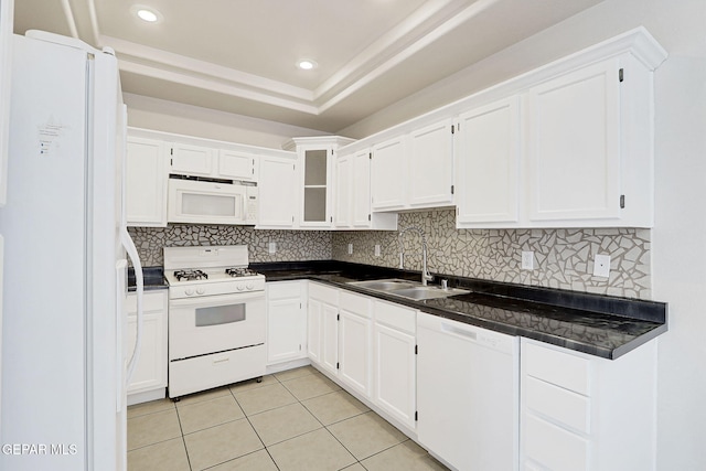 kitchen featuring a sink, white appliances, dark countertops, and light tile patterned floors