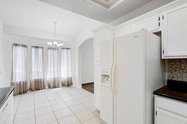 kitchen featuring white cabinets, light tile patterned floors, white refrigerator with ice dispenser, and lofted ceiling