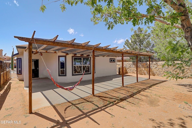 rear view of house with a patio, stucco siding, a pergola, and a fenced backyard