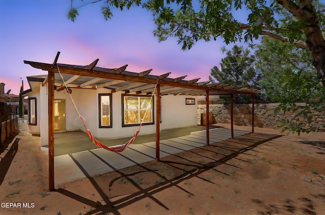 exterior space with a patio, stucco siding, a pergola, and fence
