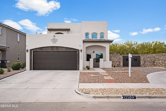 mediterranean / spanish-style house featuring a gate, driveway, stucco siding, and a fenced front yard