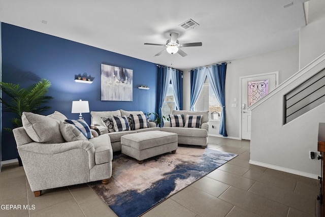 living room with ceiling fan, baseboards, and stairway