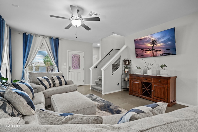 living room featuring stairway, ceiling fan, baseboards, and tile patterned flooring