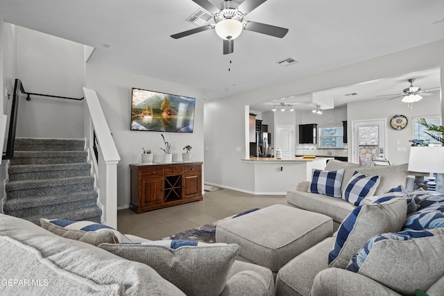 living room with a ceiling fan, baseboards, stairs, and light tile patterned floors