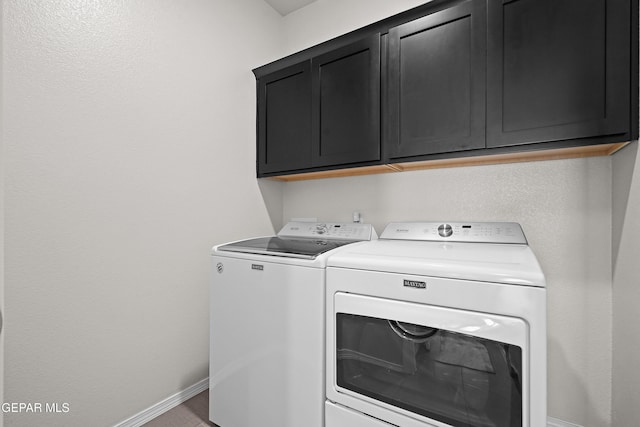 laundry area featuring washing machine and dryer, cabinet space, and baseboards