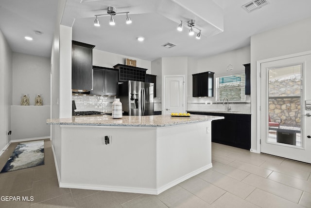 kitchen featuring stainless steel refrigerator with ice dispenser, dark cabinets, decorative backsplash, and light tile patterned floors