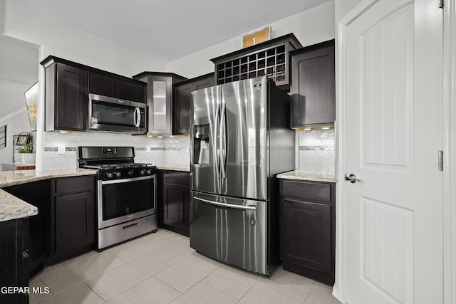 kitchen with appliances with stainless steel finishes, backsplash, light stone countertops, and light tile patterned floors