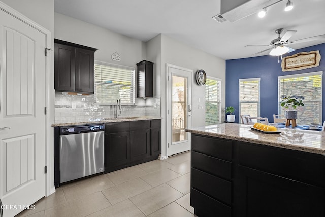 kitchen featuring dishwasher, a sink, dark cabinets, and plenty of natural light
