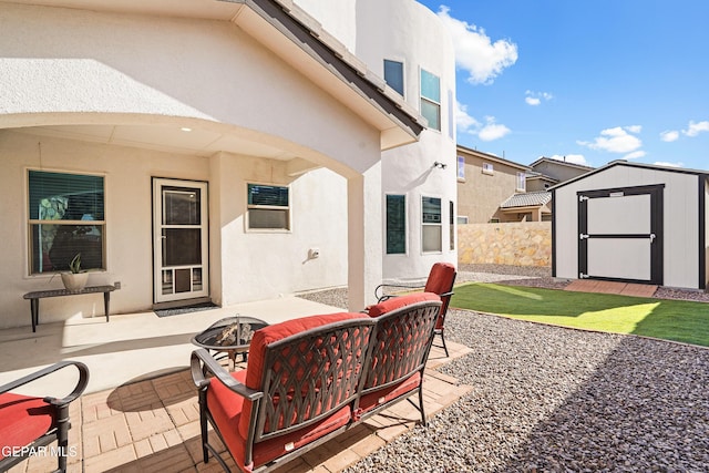 view of patio / terrace with a fire pit, a storage unit, an outdoor structure, and fence