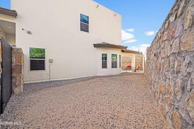 rear view of house featuring stucco siding and a patio area