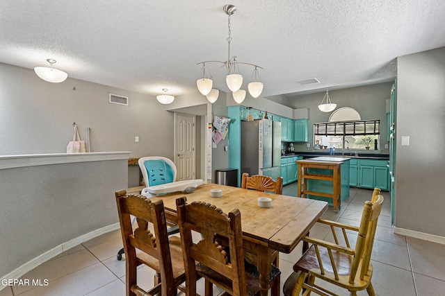 dining area with a textured ceiling, light tile patterned floors, and baseboards