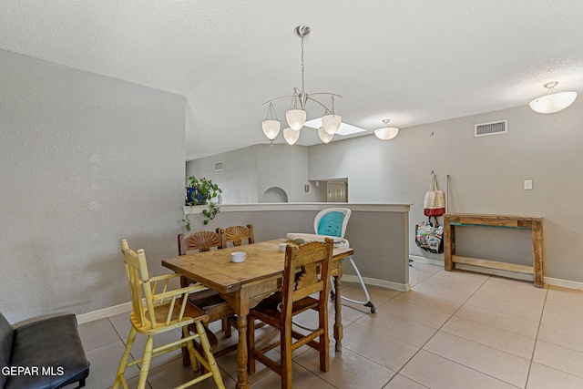 dining space featuring light tile patterned flooring, a textured ceiling, visible vents, a textured wall, and baseboards