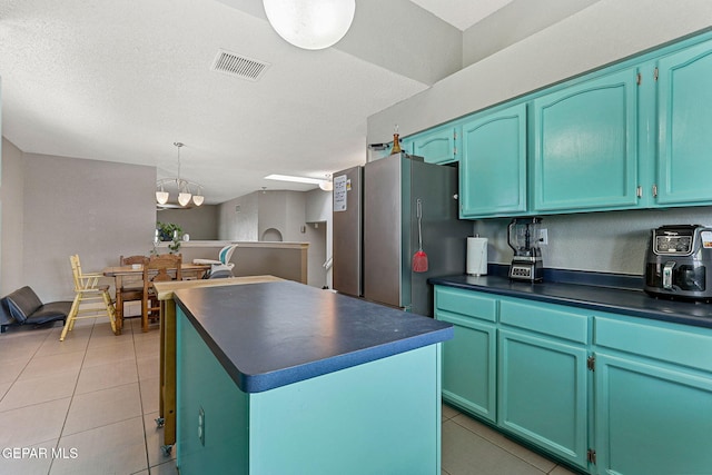 kitchen featuring freestanding refrigerator, visible vents, a chandelier, light tile patterned floors, and dark countertops