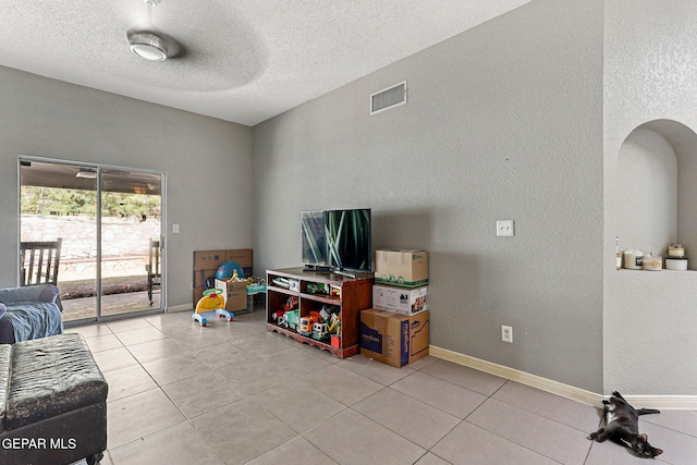 living area with light tile patterned floors, visible vents, and a textured wall