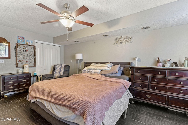 bedroom with dark wood-style flooring, a textured ceiling, a closet, and ceiling fan