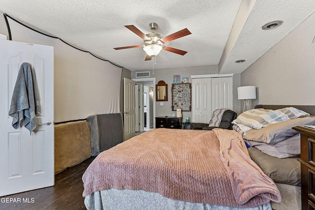 bedroom featuring a closet, visible vents, a textured ceiling, and wood finished floors
